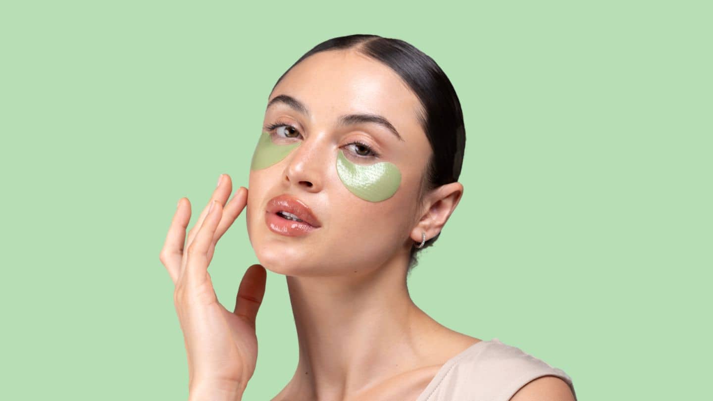 woman on a green background wearing cool crush depuffing under eye patches