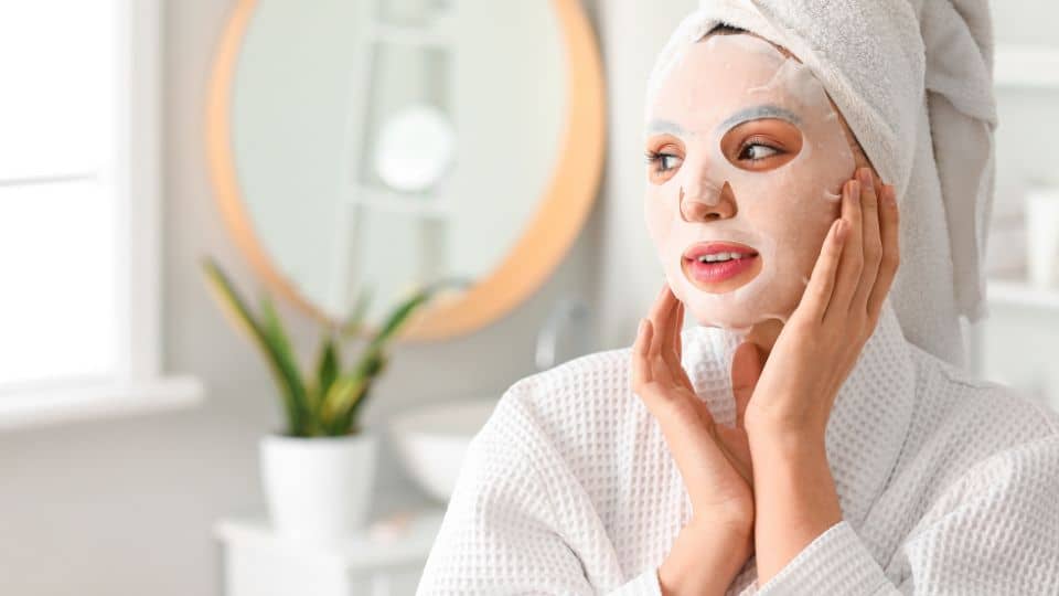 Smiling woman holding face sheet mask