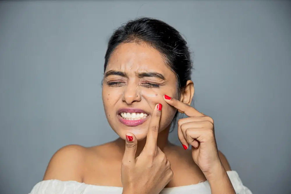 Woman with a stressed face pokes at her skin