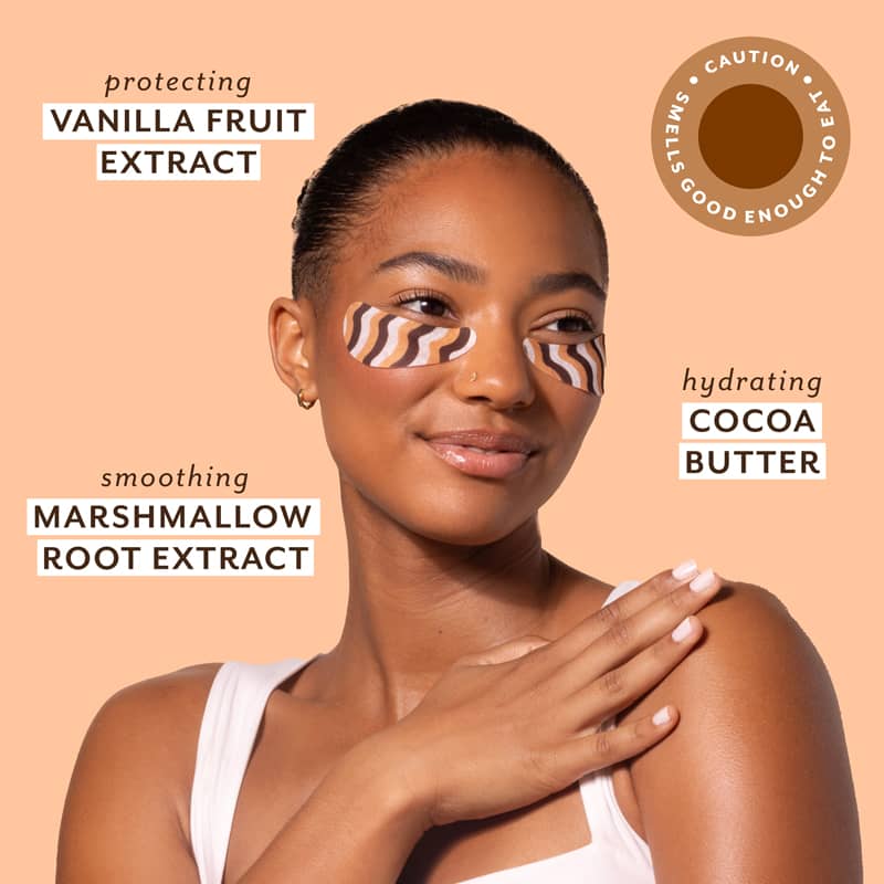 Woman applying cream to shoulder with text about vanilla fruit extract, cocoa butter, and marshmallow root extract on a peach background.