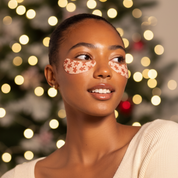 Woman with decorative face paint in front of a Christmas tree