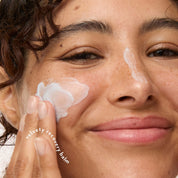 Close-up of a person applying a white five-to-nine cream balm to their cheek, with another balm patch visible on their nose. The text 'velvet recovery balm' is overlaid on the hand.