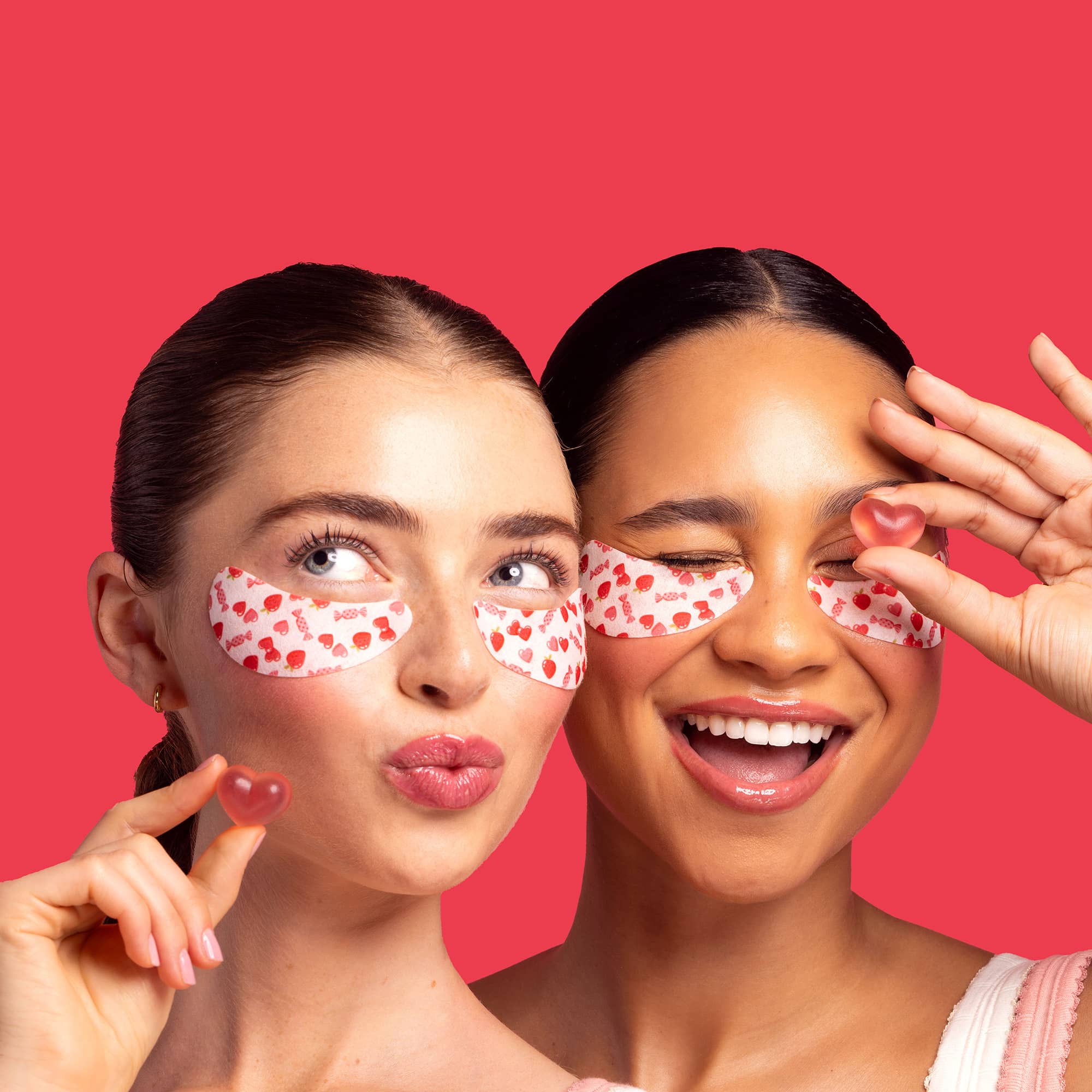 Two women wearing eye masks with a red background