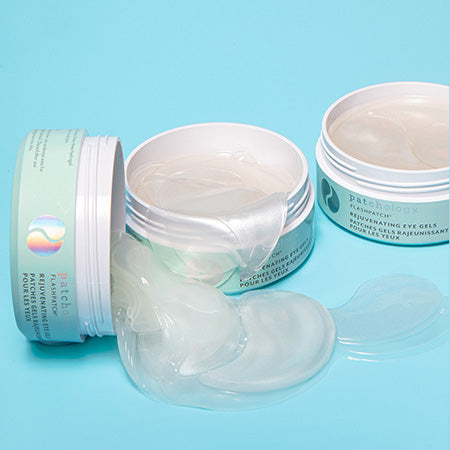 Patchology Rejuvenating Eye Gels jars with clear gel patches spilled out, hydrating under-eye treatment on blue background
