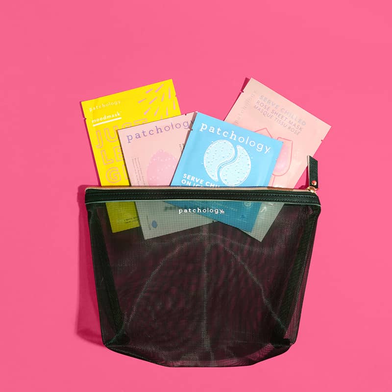 Patchology skincare sachets packed in a black mesh travel pouch on a bright pink background.
