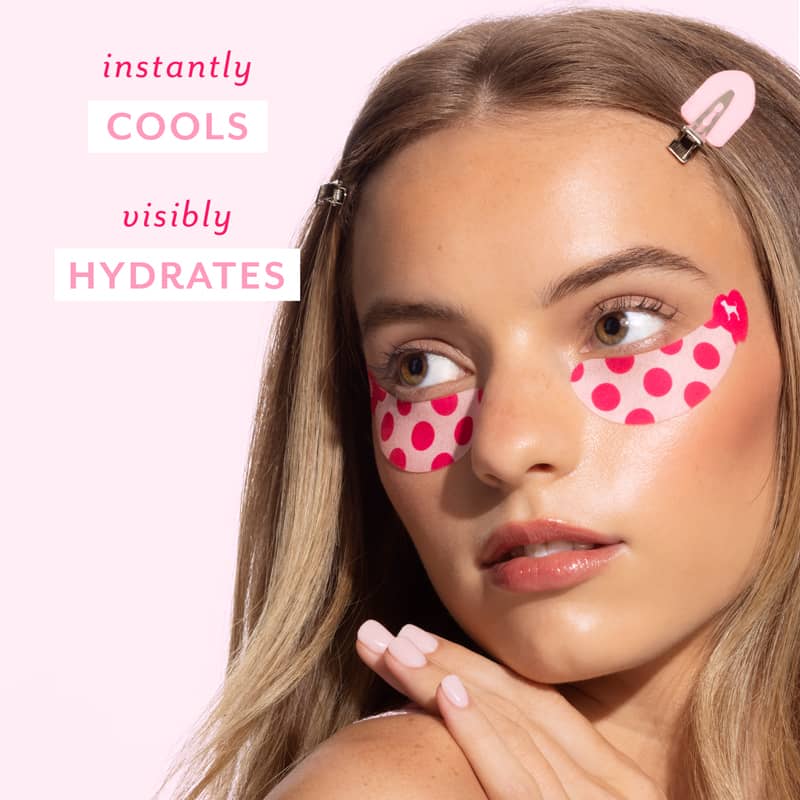 A close-up of a woman with pink and red polka dot eye patches on her cheeks, against a light pink background with text that reads 'instantly COOLS visibly HYDRATES'.