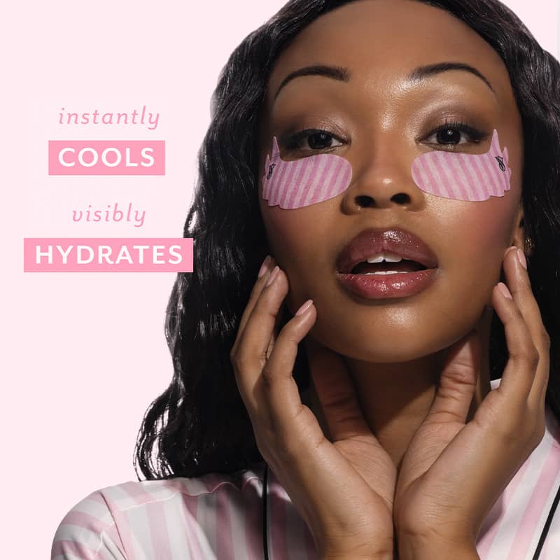 A woman with pink striped eye patches on her face, posing against a light pink background with text that reads 'instantly COOLS visibly HYDRATES'.