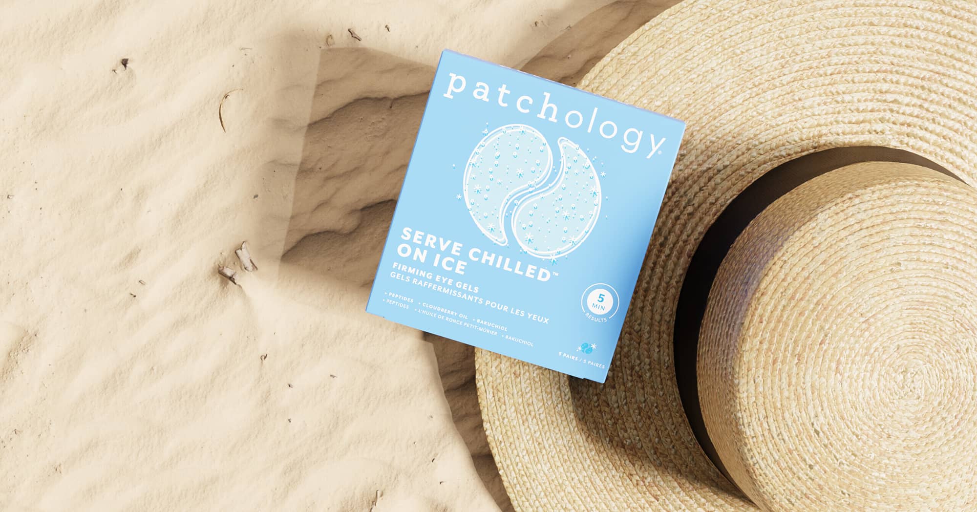 Patchology product packaging on sand with a straw hat