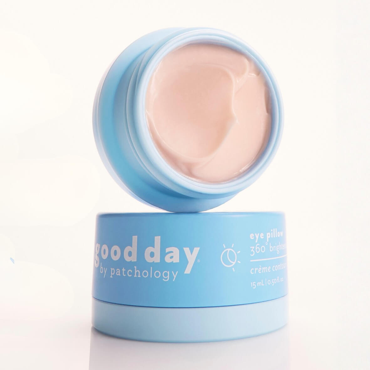A light blue cosmetic jar of Good Day eye cream with the lid off, showing a pale peach-colored cream inside, set against a clean white background.