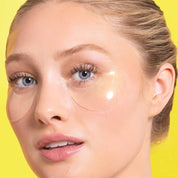 Woman wearing eye patches against a yellow background