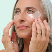 Woman applying eye patches with a light blue background