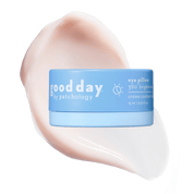 A light blue cosmetic jar with product information centered over a large pale pink cream smear on a solid background.