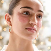 Close-up of a woman's face with pink patches on her cheeks against a blurred background